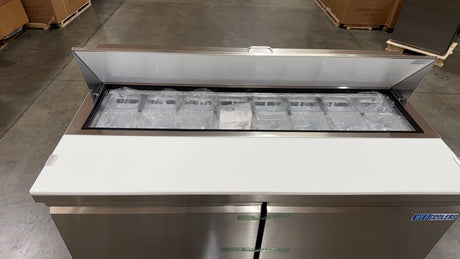 Stainless steel refrigerator with glass door in a warehouse setting