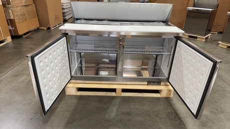 Stainless steel refrigerator on a pallet in a warehouse setting