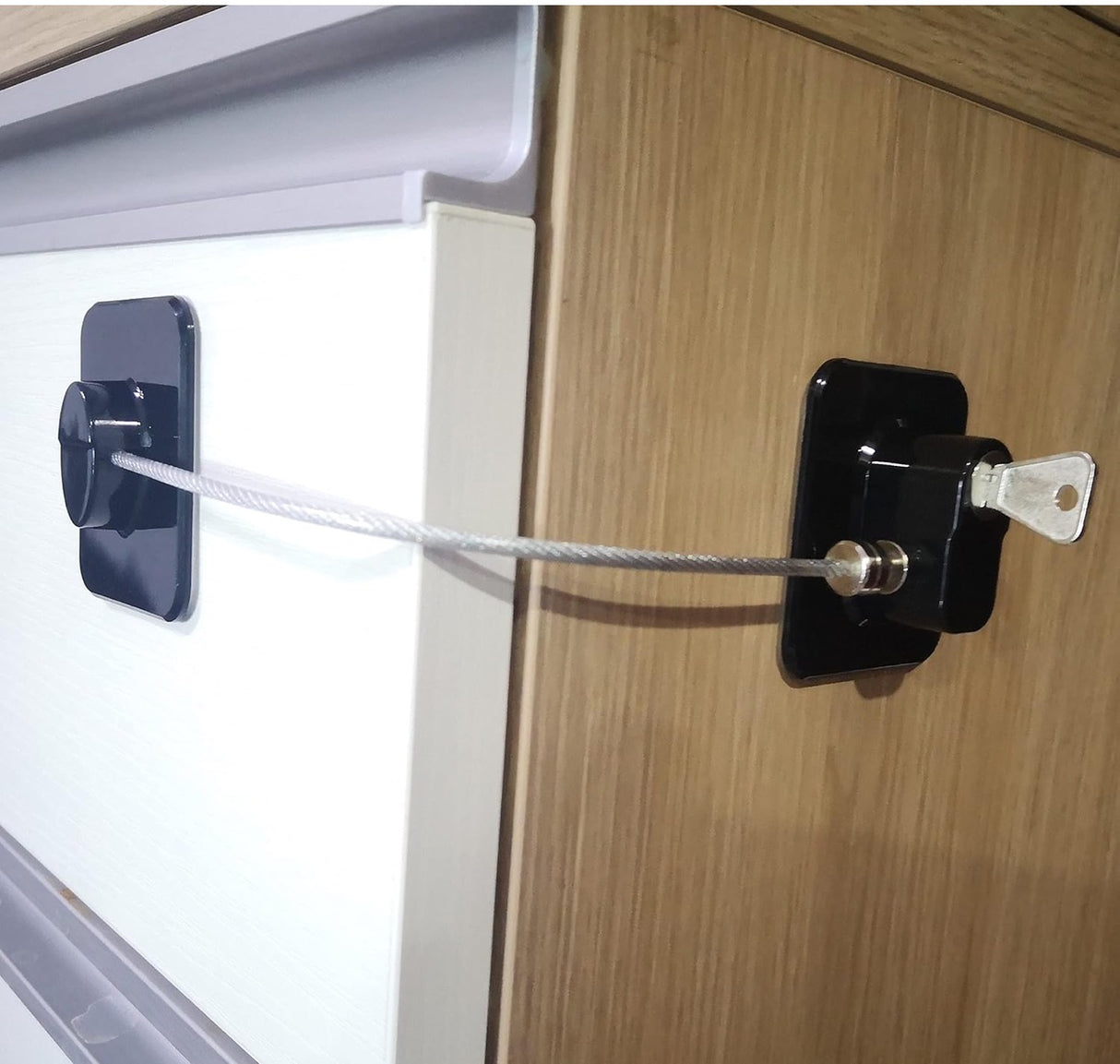 Cable lock attached to a wooden cabinet with a white background