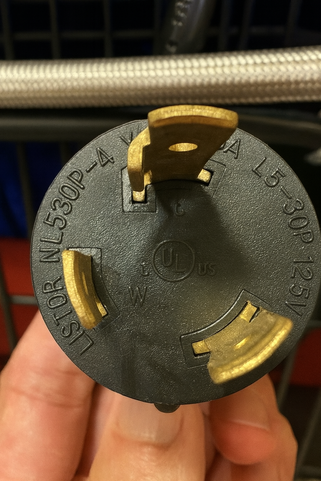 Electrical plug held in a hand with a blurred background