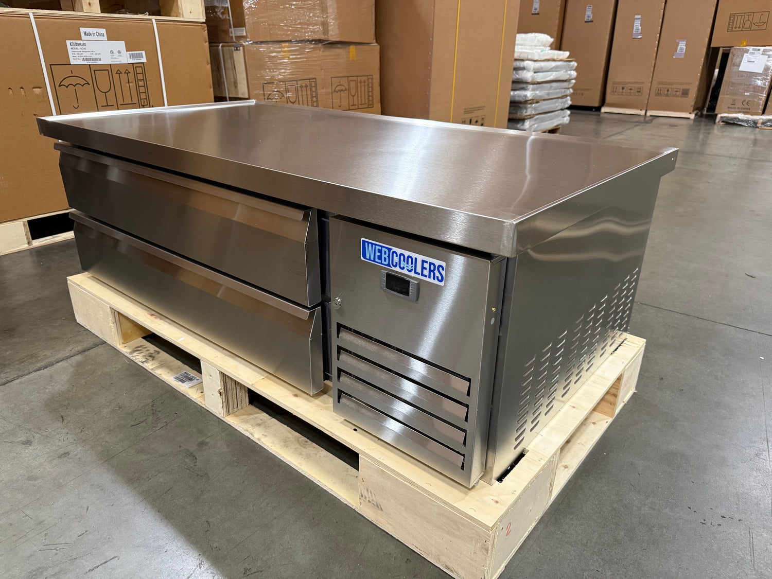 Stainless steel refrigerator on a wooden pallet in an industrial setting