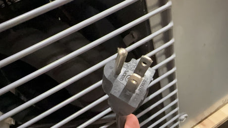 Hand holding a plug near an air conditioner with white grille