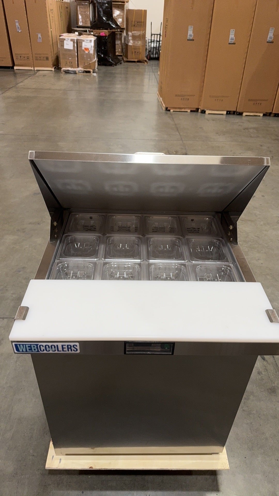 Stainless steel cooler with ice bins on a pallet in a warehouse setting