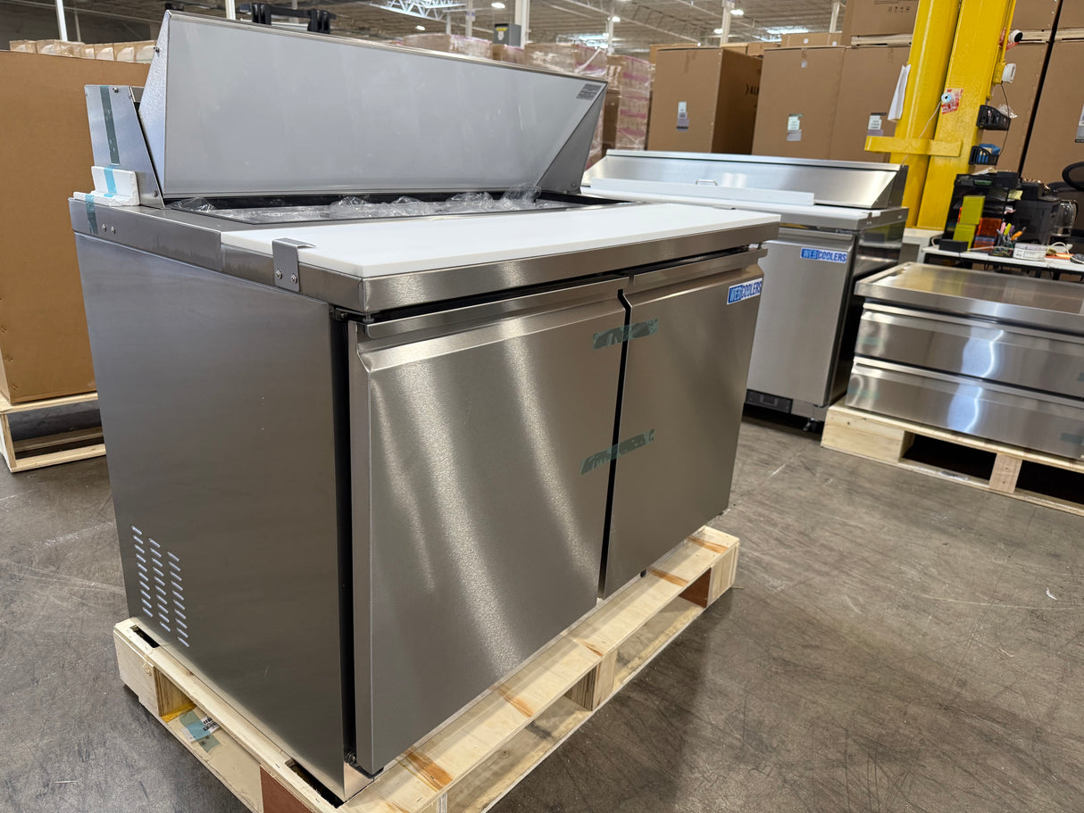 Stainless steel industrial refrigerator on a pallet in a warehouse setting