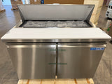 Stainless steel refrigerator with open door in a warehouse setting