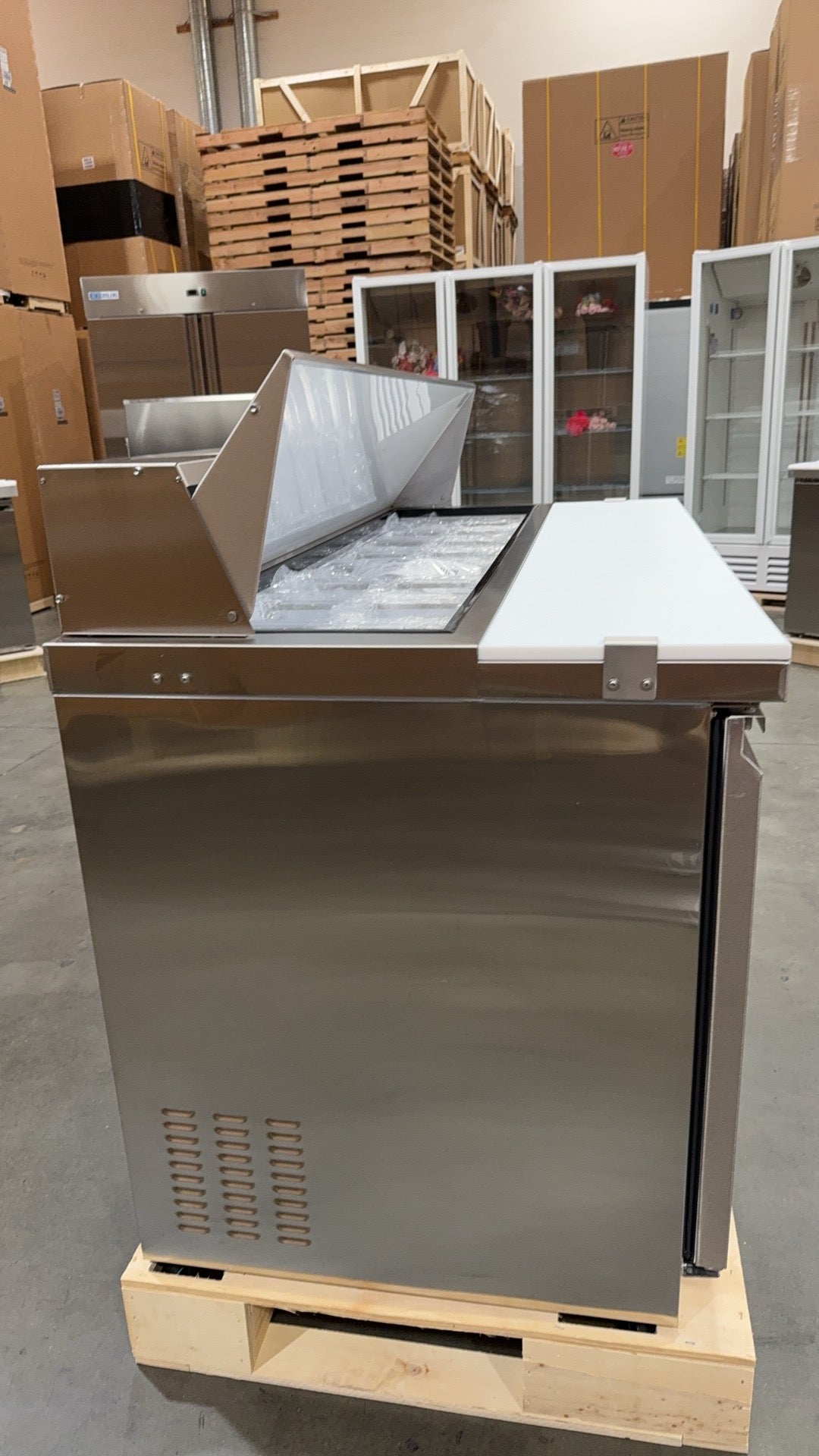 Stainless steel industrial oven on a wooden pallet in a warehouse setting
