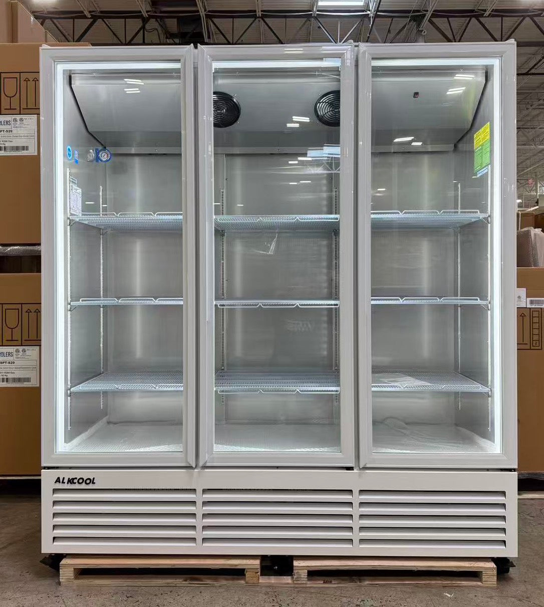 Triple-door glass refrigerator on a pallet in a warehouse setting
