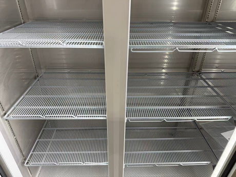 Empty metal shelves inside a refrigerator or freezer unit.
