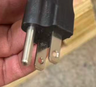 Close-up of a metal plug with a wooden surface in the background