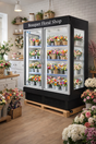 Floral shop refrigerator with flower arrangements displayed inside, surrounded by flowers on a wooden floor.