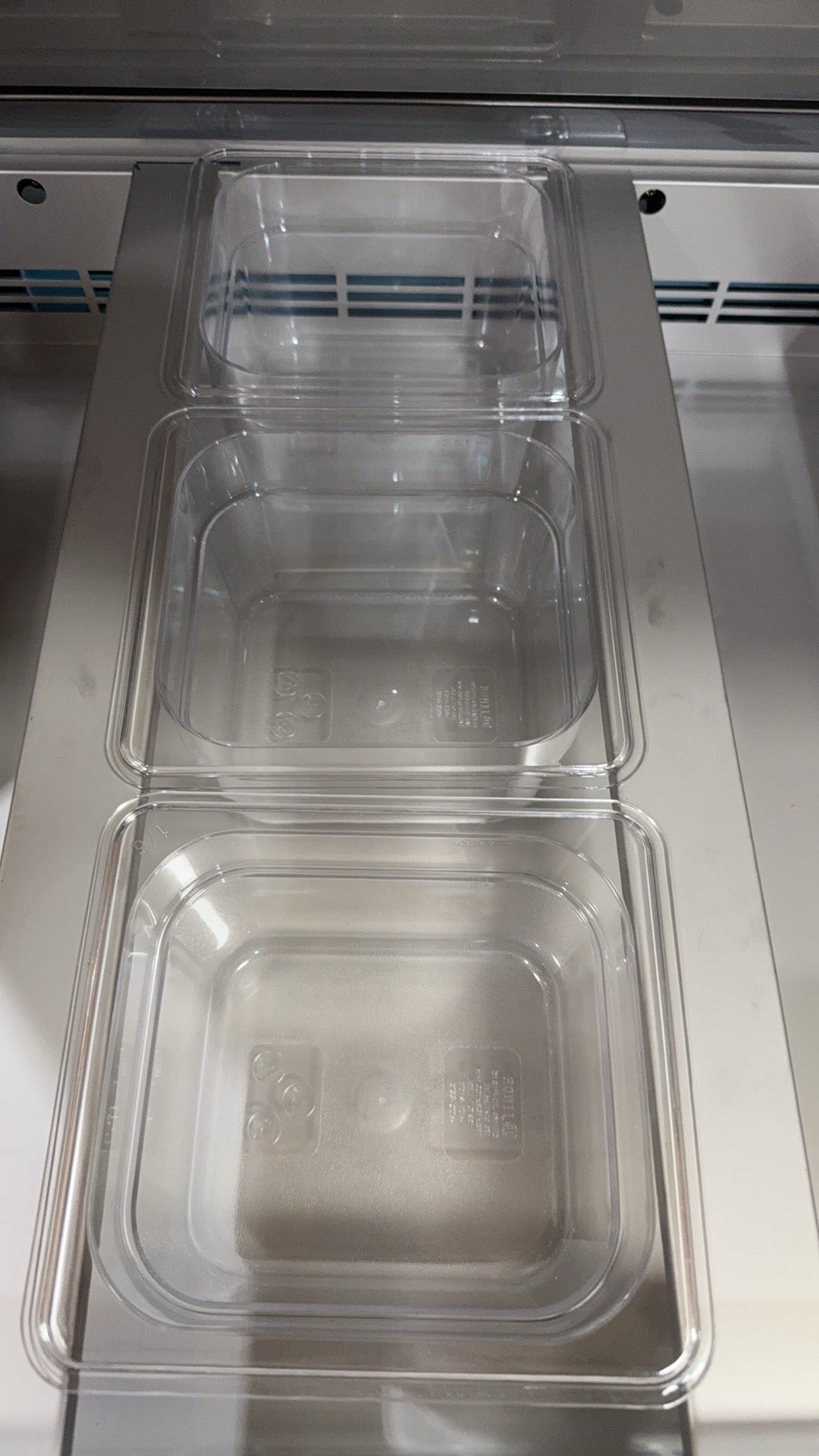 Clear plastic containers stacked inside a metal compartment