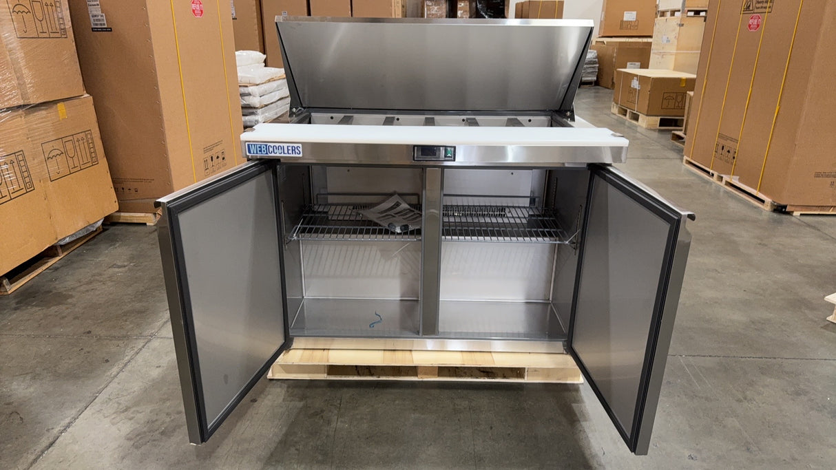 Stainless steel kitchen cabinet with open doors in a warehouse setting