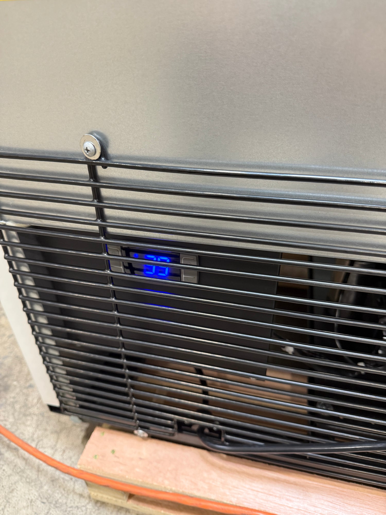 Outdoor air conditioning unit with a digital display on a wall.