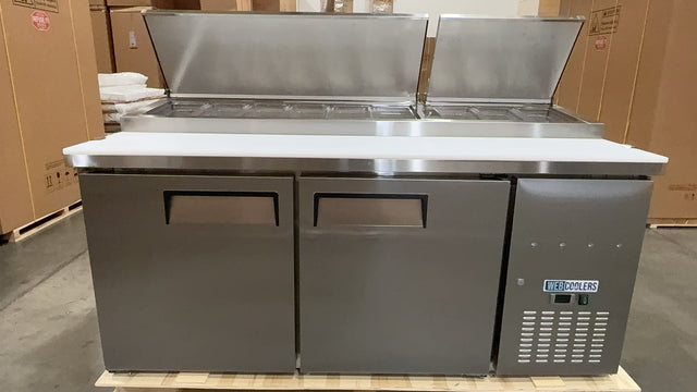 Stainless steel commercial refrigerator on a pallet with cardboard boxes in the background