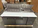 Stainless steel refrigerated counter with open doors in a warehouse setting